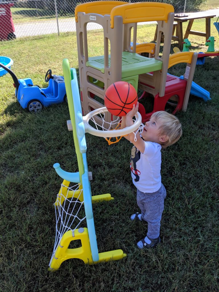toddler playing with basketball hoop