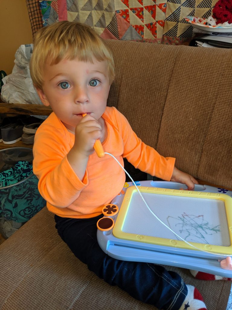 toddler scribbling on magnetic drawing board