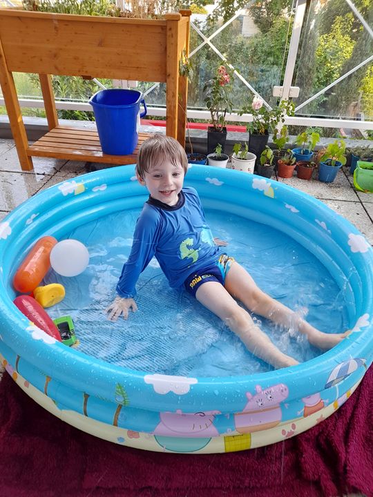 toddler in Peppa Pig pool on balcony