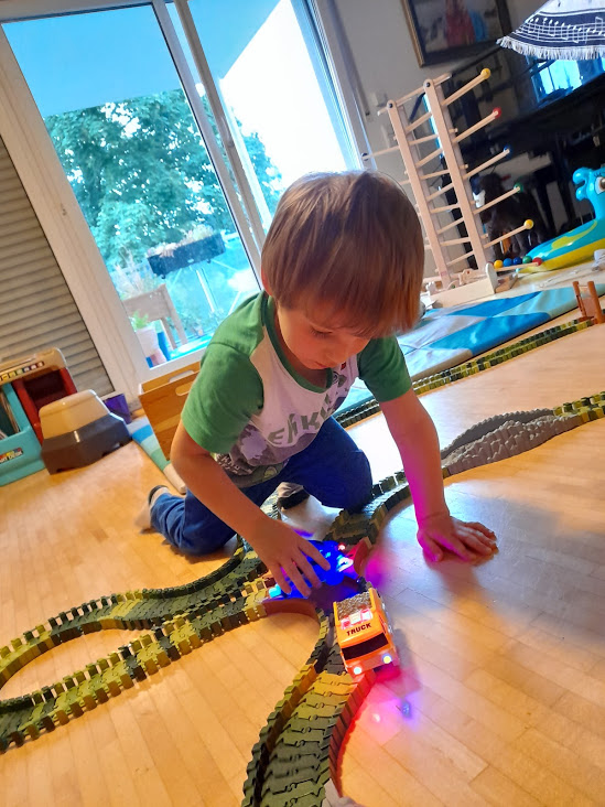toddler playing with track cars with LED lights